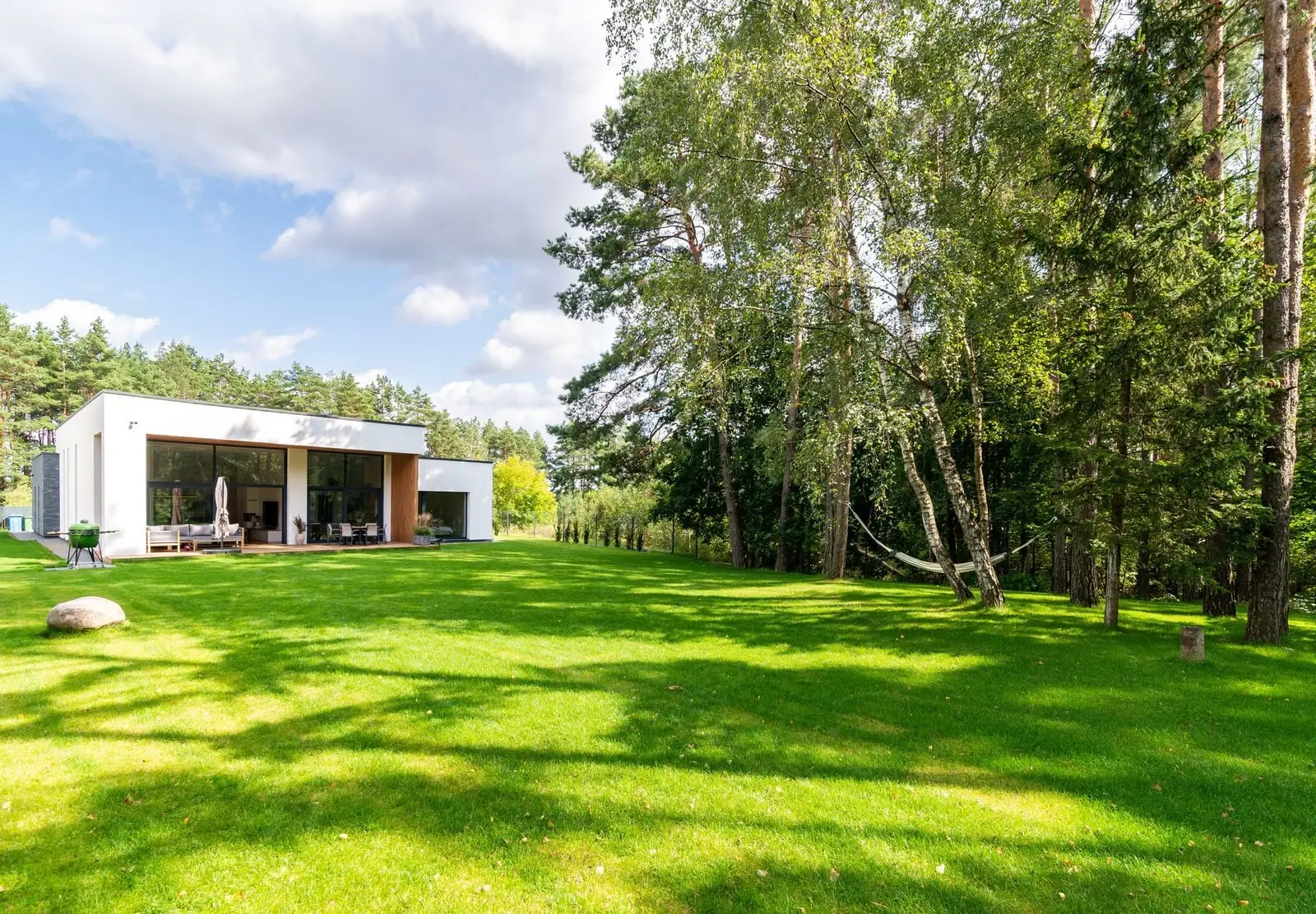 A modern house with a large front lawn surrounded by mature shade trees in Spring Hill, Florida