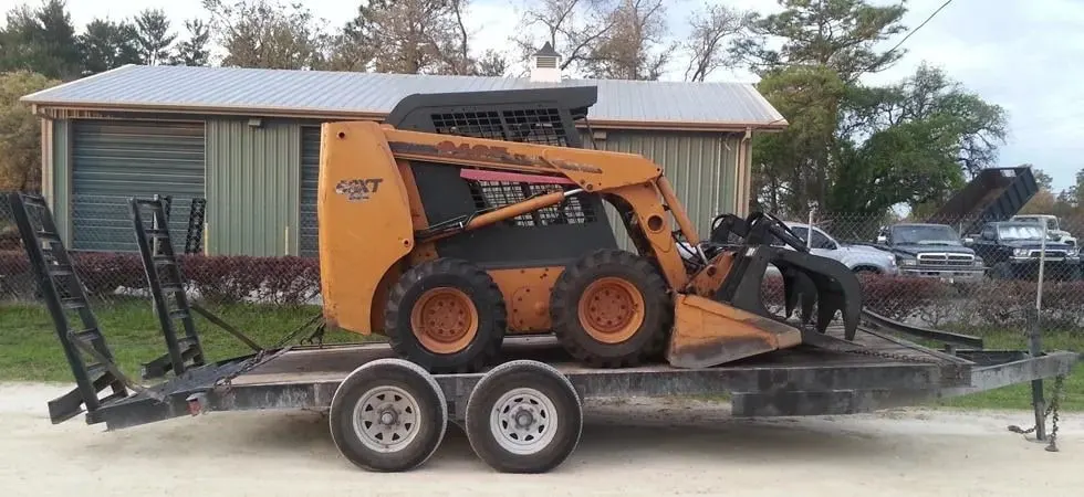 A skid steer loaded on a trailer, part of The Rite Guys Tree Service equipment fleet